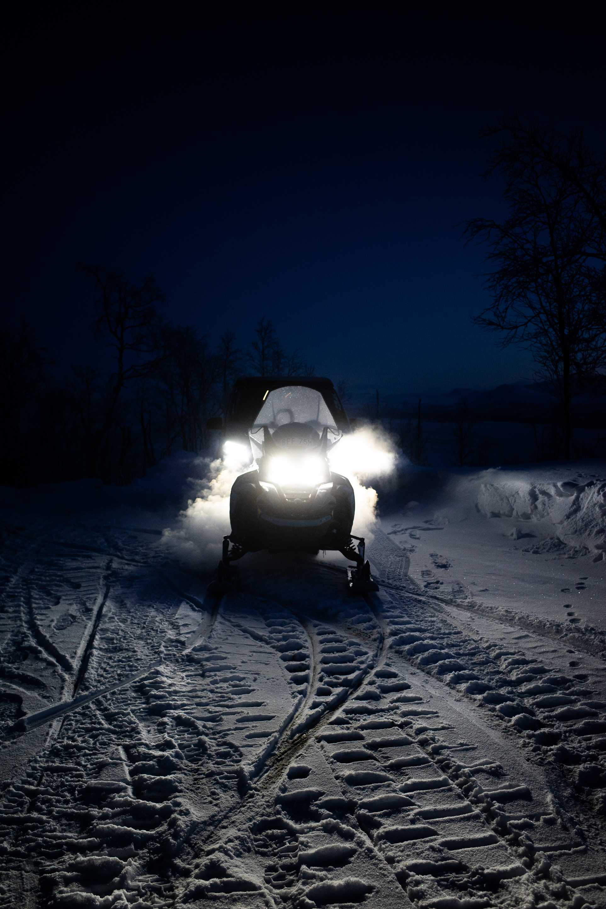 Schneemobil mit Scheinwerfern bei Nacht